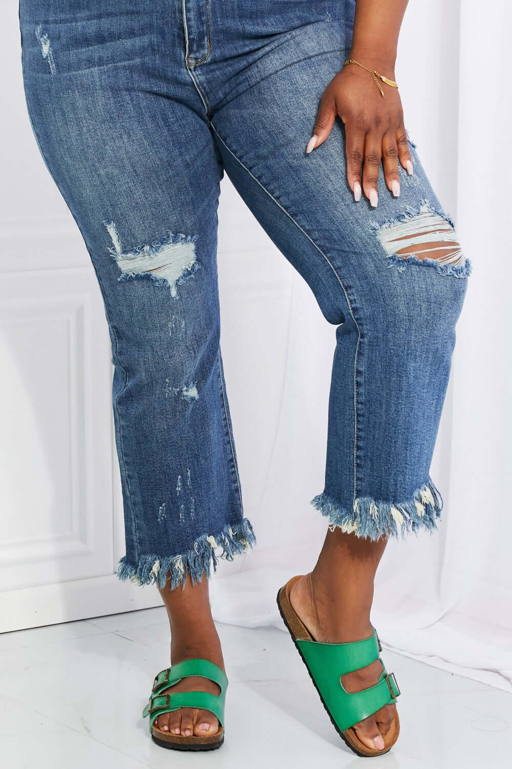 Woman wearing Risen Jeans' distressed undone chic straight leg jeans with raw hem and green sandals