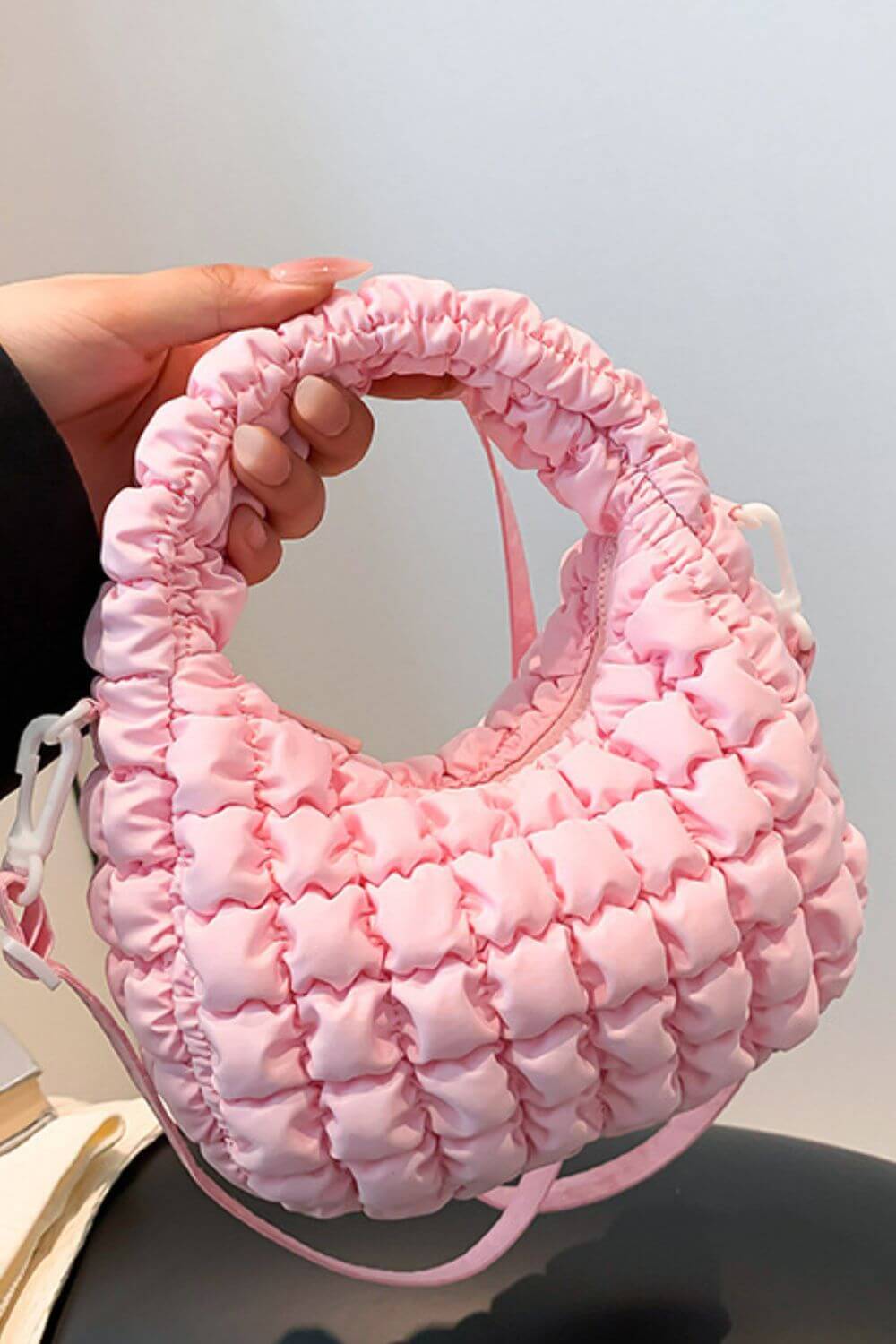 Pink quilted puffy crossbody bag with removable strap and unique design, perfect for fashion-forward versatility.