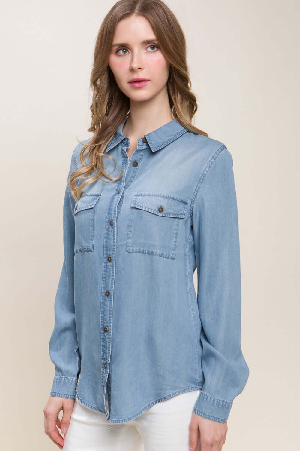 Woman wearing scooped hem button up denim shirt with long sleeves and collar