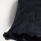 Black Bella Road Fuzzy Hem Cable-Knit Poncho draped on a plush chair, showcasing its cozy texture and stylish design.