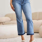 Woman wearing Release Hem Cropped Bootcut Judy Blue Jeans styled with white heels in a modern living room.