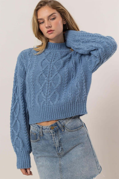 Cozy blue cable-knit mock neck sweater with dropped shoulders, perfect for chic winter outfits.