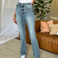 Woman wearing Judy Blue medium rise bootcut jeans, showcasing the classic fit and slight flare against a stylish indoor setting.