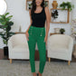 Woman wearing FAM-FAM High Waist Skinny Pants in green with decorative buttons, posing stylishly in a modern living room.