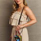 Woman wearing beige outfit holds Nicole Lee USA small crossbody wallet with floral pattern and adjustable strap.