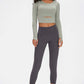 Model showcasing the Millennia Long Sleeve Cropped Top in green paired with gray leggings, perfect for stylish workouts.