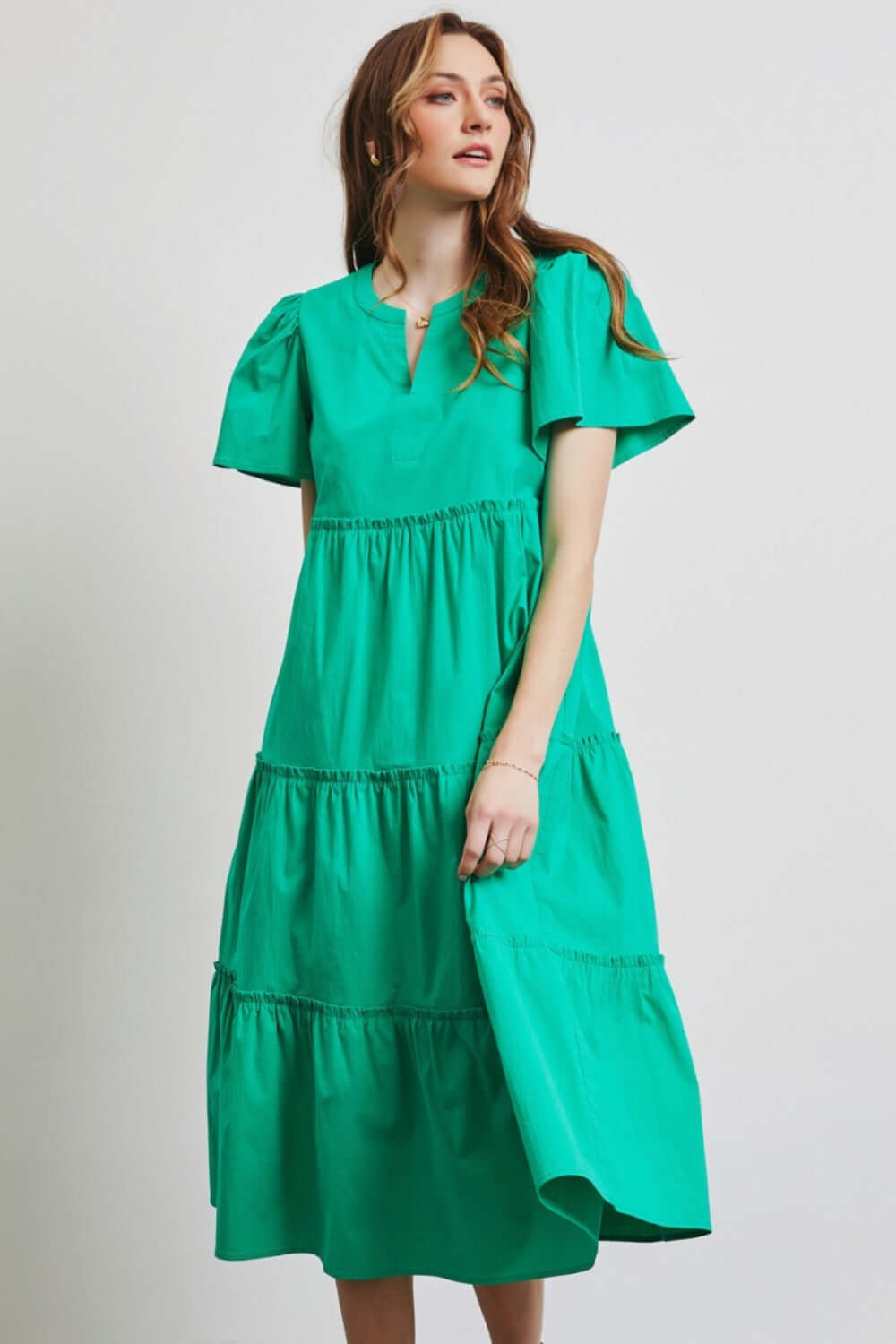 Woman wearing green HEYSON cotton poplin ruffled tiered midi dress, perfect for summer occasions.