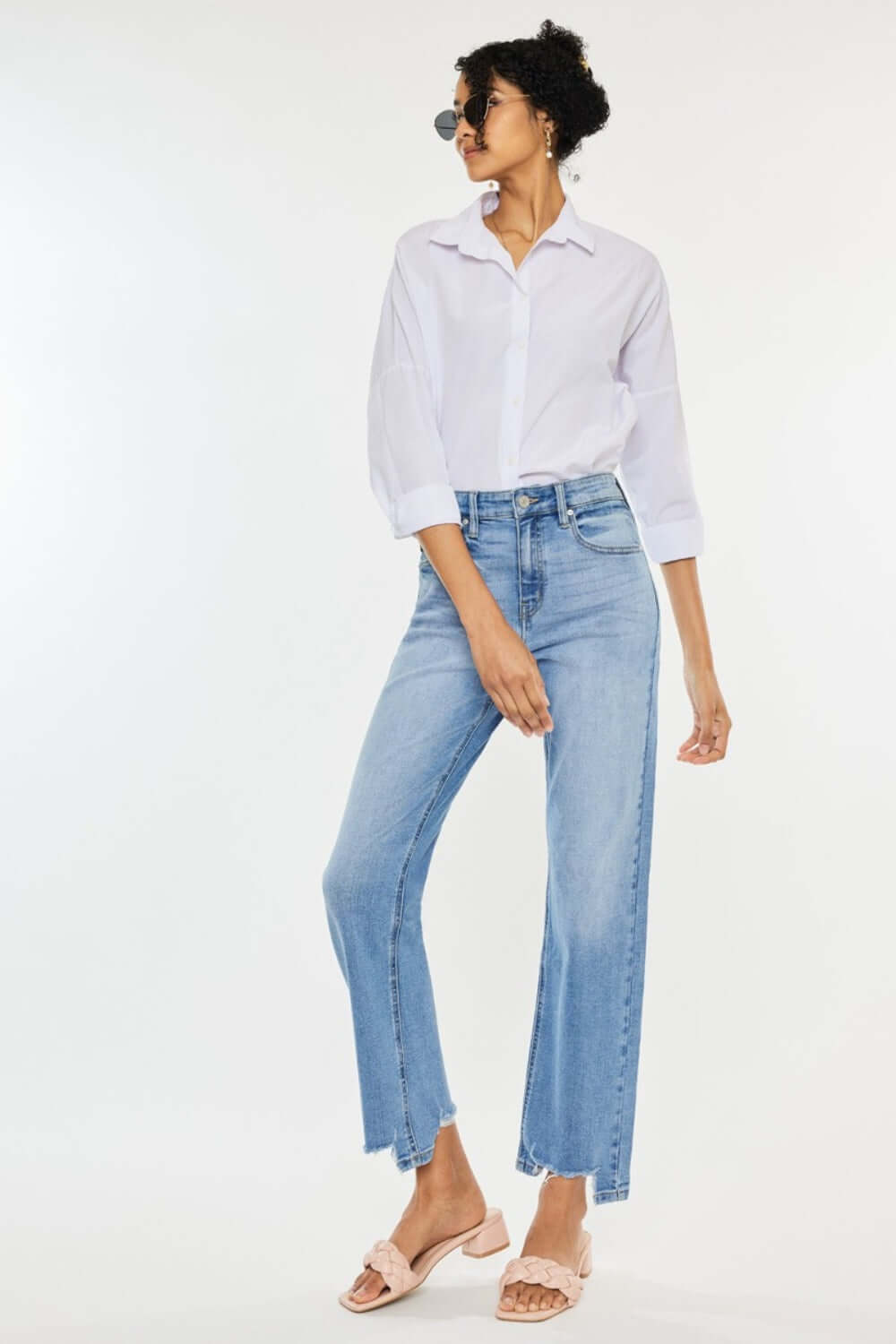 Woman wearing high waist raw hem straight jeans paired with white shirt and sandals, showcasing flattering fit and timeless style.