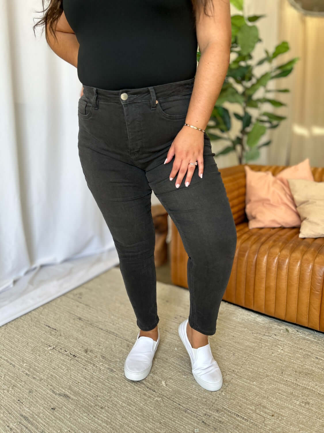 Woman wearing RFM Full Size High Rise Tummy Control Skinny Jeans in black, showcasing the flattering high-waist design and sleek fit.