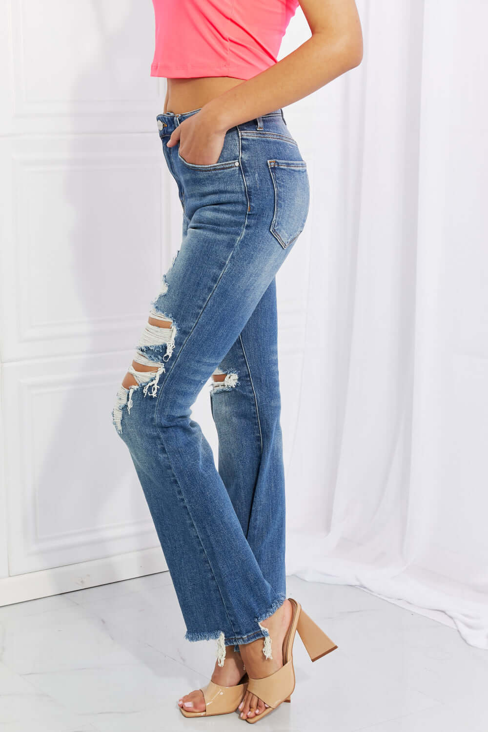 Hazel High Rise Distressed Flare Jeans with frayed hem and pockets, side view on model. Perfect for rocker style with Risen Jeans quality.