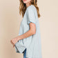 Woman wearing a contrast trim short sleeve slit T-shirt in light grey, paired with blue jeans, showcasing side slit and relaxed fit.