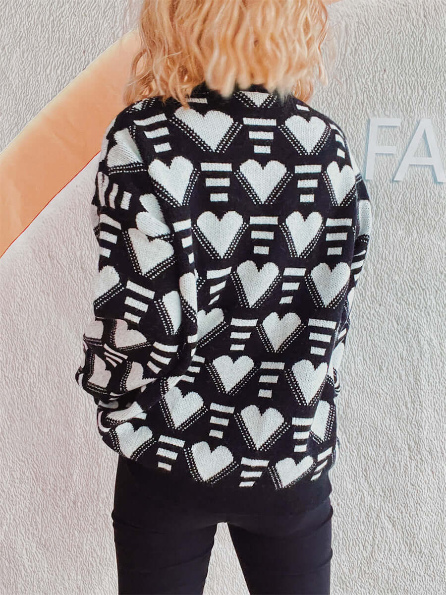 Woman wearing Bella Heart Sweater with black and white heart contrast design, dropped shoulder, and slightly stretchy fabric.