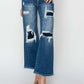 High rise patch detailed wide leg crop jeans in dark blue denim. Trendy Risen Jeans with edgy patches and flattering silhouette for a modern look.