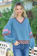 Trendy woman in blue Hailey & Co color block V-neck cropped sweatshirt outdoors, showcasing a stylish and sporty fashion look