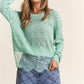 Woman wearing J.NNA Lace Detail Long Sleeve Knit Top in mint green with intricate lace accents, styled with wide-leg jeans.