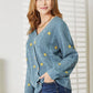 Woman wearing a blue floral embroidered cable knit cardigan, perfect for a cozy and stylish look.