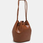 Brown drawstring bucket bag crafted from pebbled vegan leather with knotted handle.