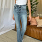 Woman wearing Judy Blue medium rise bootcut jeans with a white top, showcasing the classic flattering fit and slight flare style.