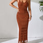 Woman wearing a rust-colored openwork scoop neck cover-up dress with tassel hem, styled with sandals and jewelry, in a semi-sheer, slightly stretchy material.