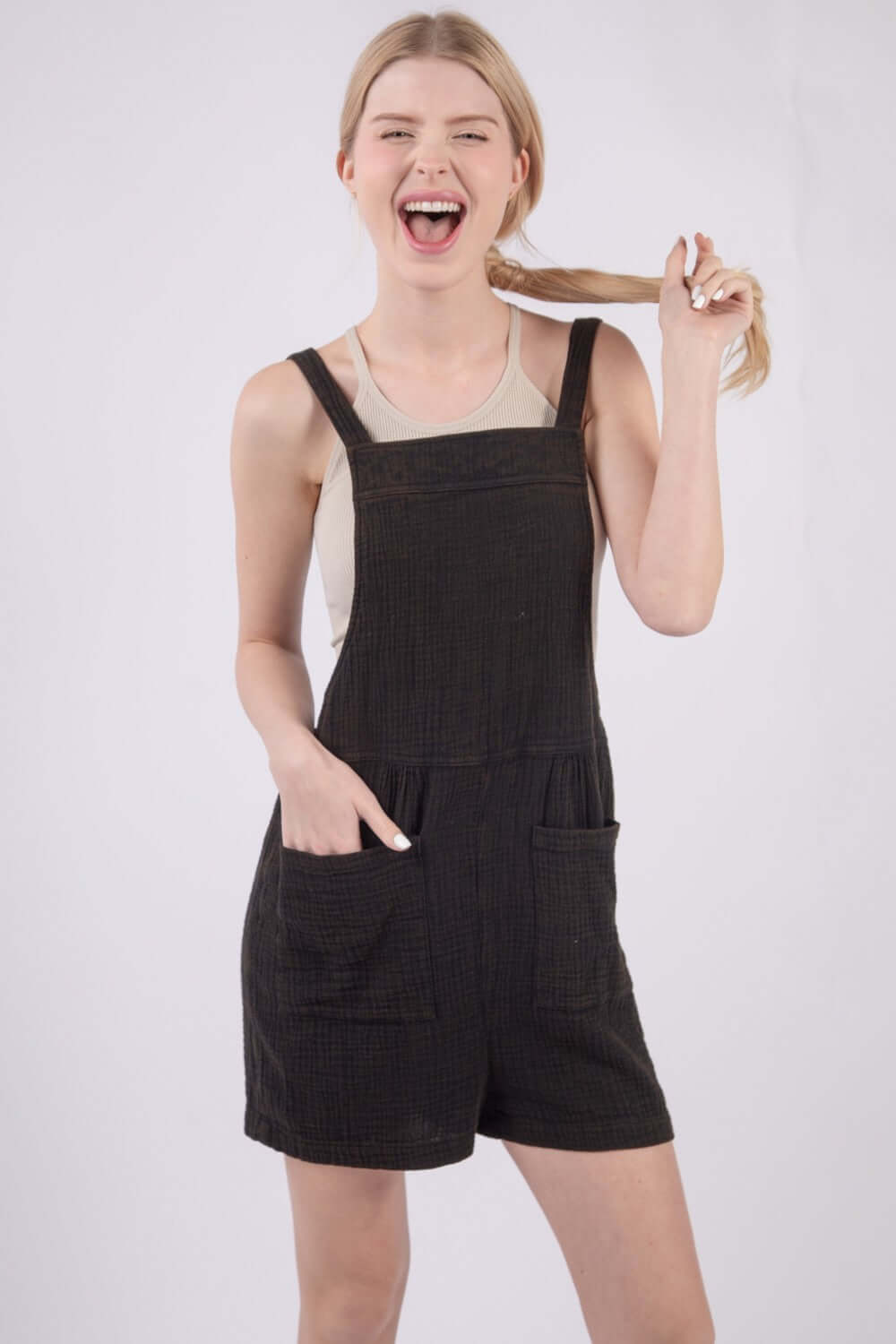 Woman wearing sleeveless double gauze overalls with pockets, featuring a square neckline and open back, perfect for casual summer wear.