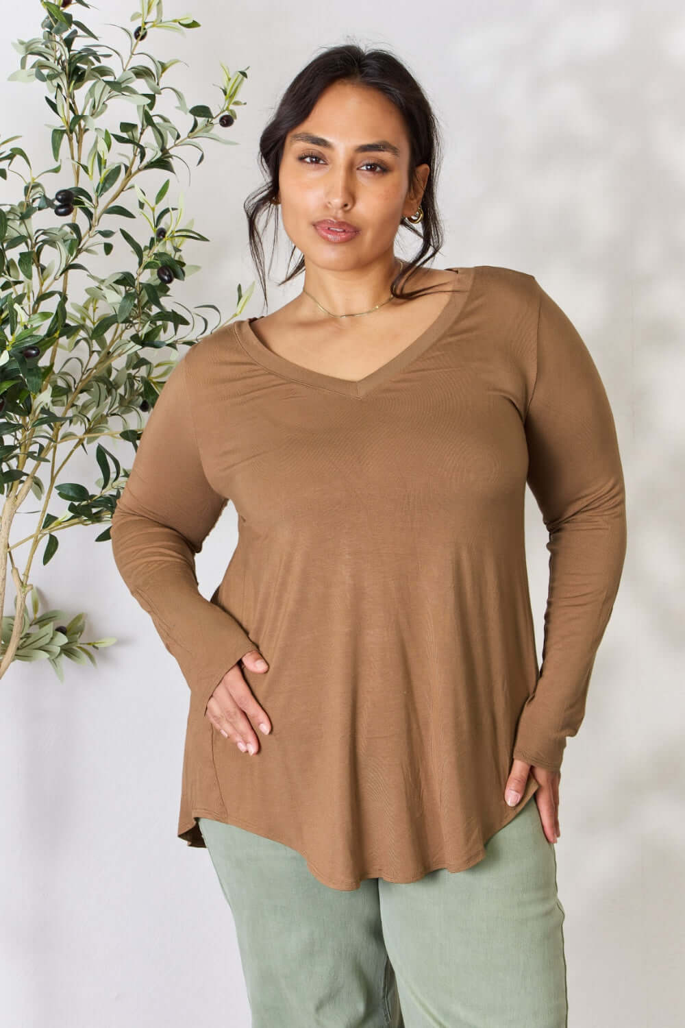 Woman wearing a long sleeve V-neck top in brown, showcasing its luxurious rayon fabric and flattering neckline.