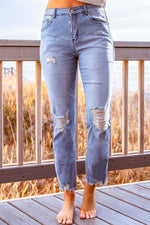 Stylish distressed cropped jeans with slight stretch in a solid pattern, featuring a casual look, photographed in a studio setting.