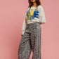 Model in a stylish LOVE sweatshirt and floral pants, showcasing a charming and cozy outfit with hat and boots.