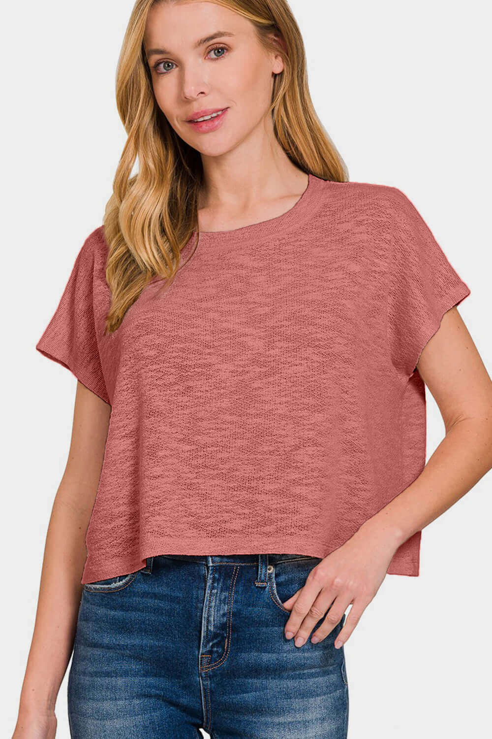 Woman wearing a casual round neck short sleeve t-shirt in a pink hue paired with blue jeans for a simple and stylish look