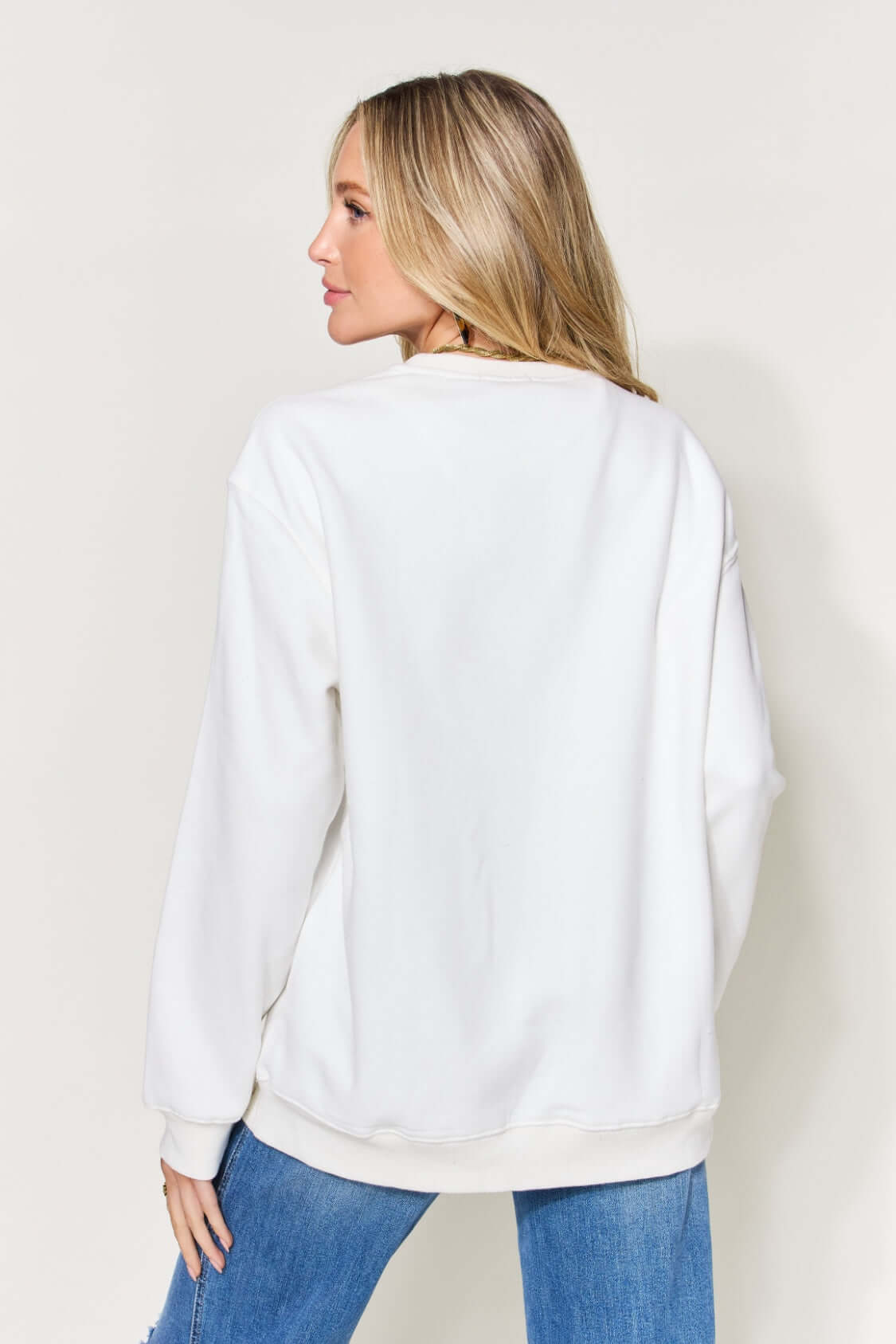 Woman wearing white letter graphic long sleeve sweatshirt in full size, back view. Casual, comfortable style perfect for everyday wear.