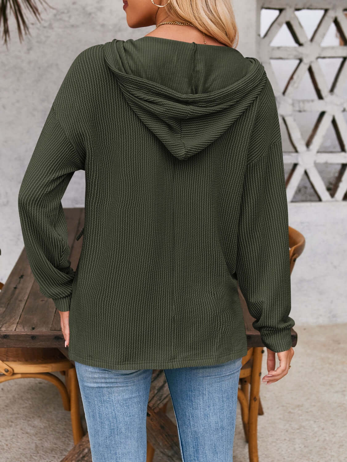 Woman wearing a drawstring dropped shoulder long sleeve hoodie in green, viewed from the back with a casual outdoor setting.