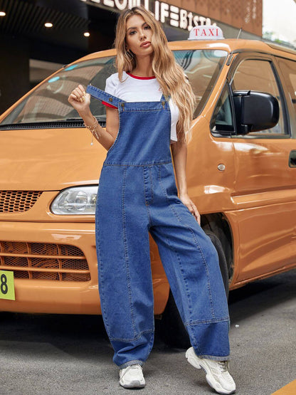 Woman in Bella Road Wide Leg Denim Overalls stands confidently in front of an orange taxi, embracing casual style and adventure.