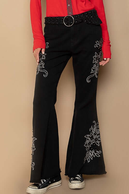 Black raw hem embroidered flare pants with a bohemian vibe, paired with a stylish red top and sneakers.