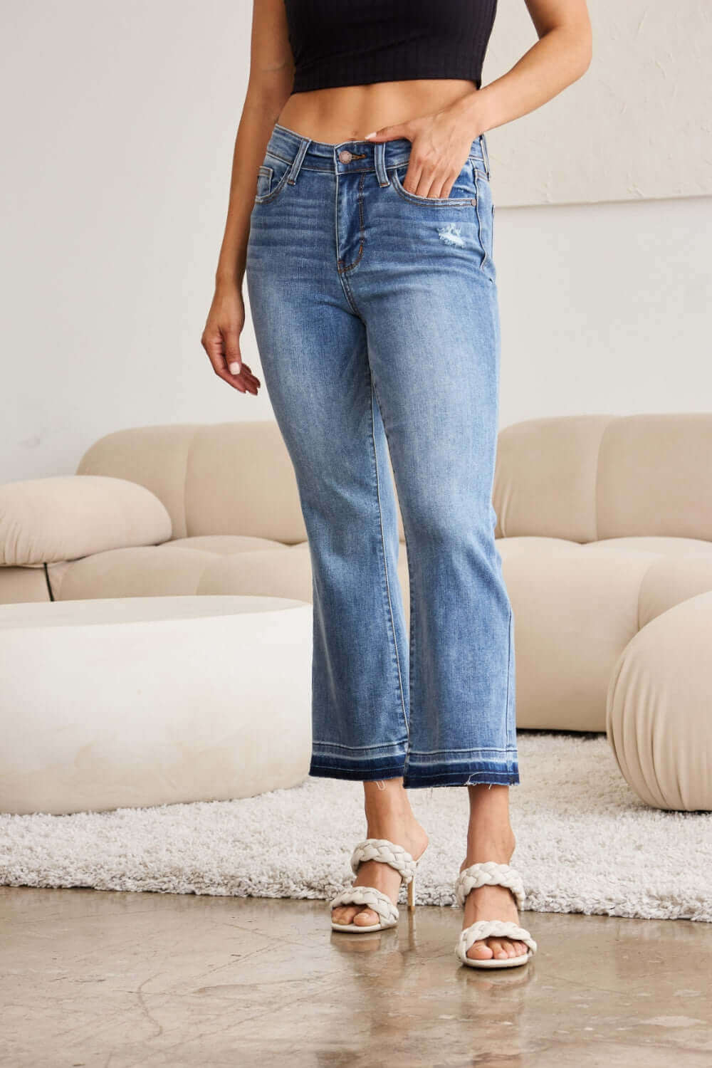 Woman wearing Judy Blue release hem cropped bootcut jeans with a modern silhouette and edgy design.