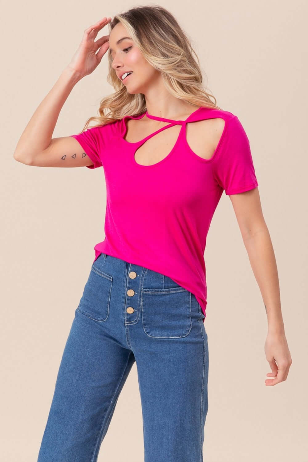 Woman wearing pink Cutout Asymmetrical Neck Short Sleeve T-Shirt with jeans showing unique neckline and stylish cutout details.