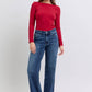 Model wearing Judy Blue Full Size Raw Hem Mid Rise Jeans with a fitted red long-sleeve top, showcasing a stylish casual look.