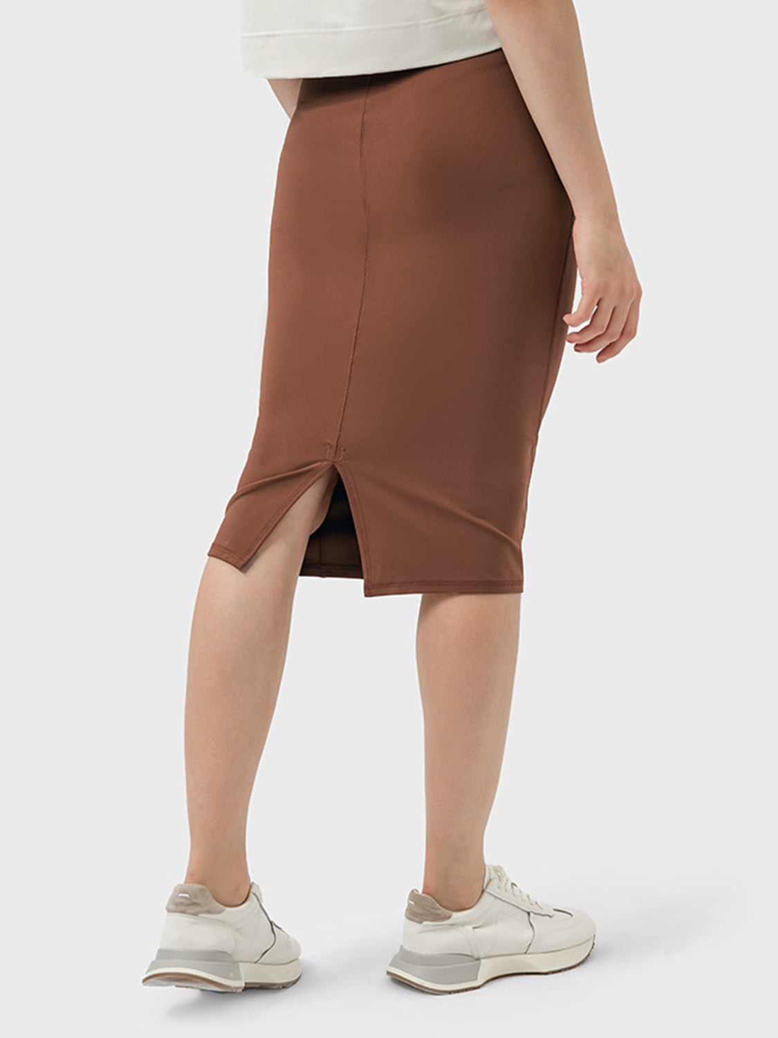 Woman wearing a brown Millennia Slit Wrap Active Skirt from the back, showcasing its stylish slit detail and stretchy material.