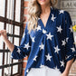 Woman wearing Heimish Full Size Roll-Tab Sleeve Star Print Top in navy with white stars, standing by a window looking stylish.