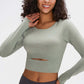 Model wearing a light green long-sleeve cropped top with a cutout, showcasing comfort and style for activewear.