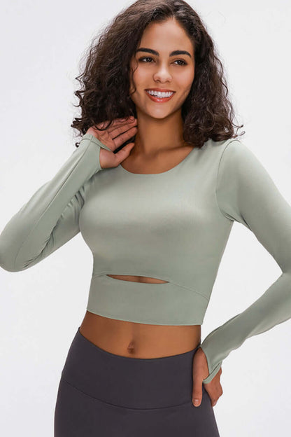 Model wearing a light green long-sleeve cropped top with a cutout, showcasing comfort and style for activewear.