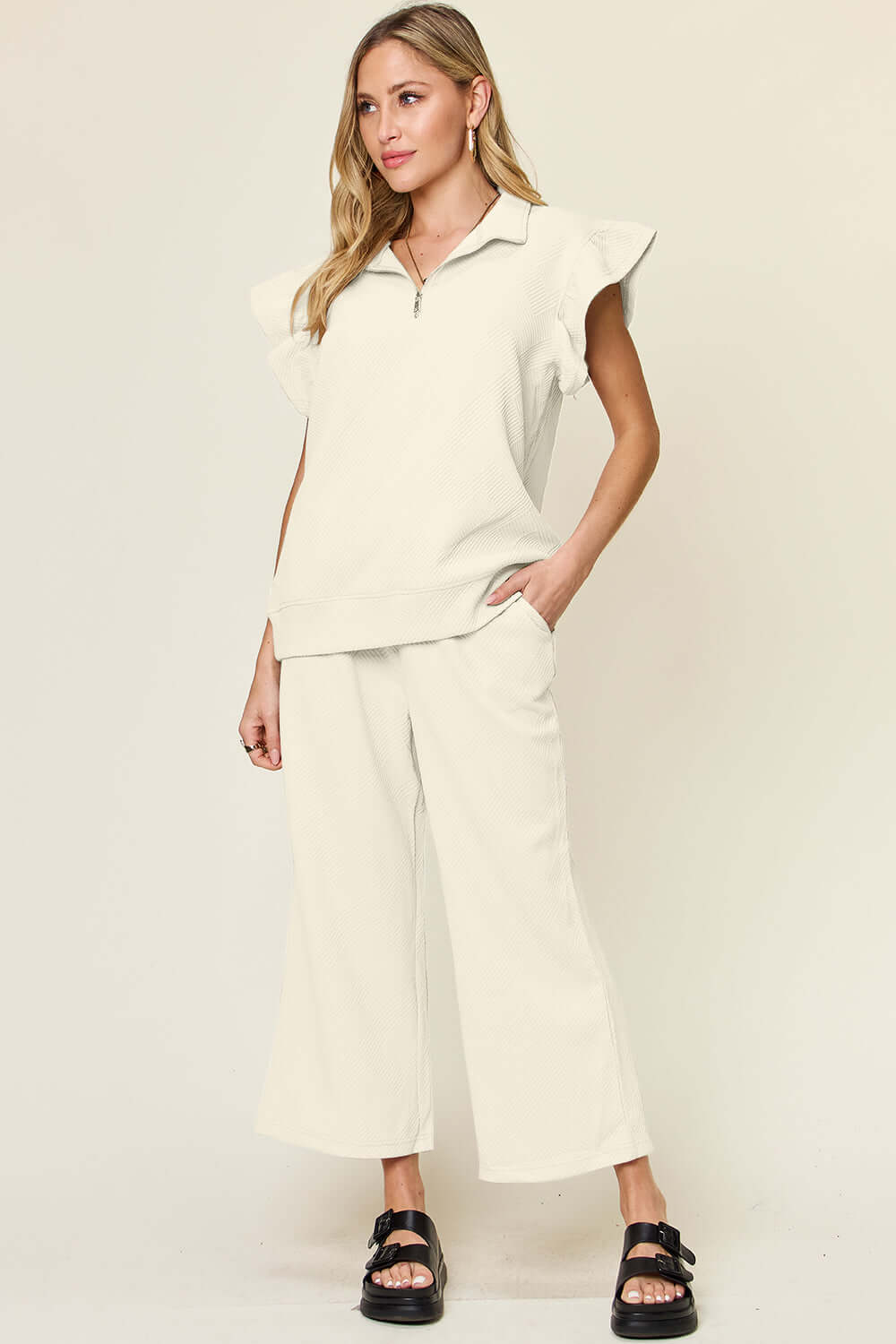 Woman wearing Texture Ruffle Short Sleeve Top and Drawstring Wide Leg Pants Set in cream color, featuring pockets and a slightly stretchy fabric.