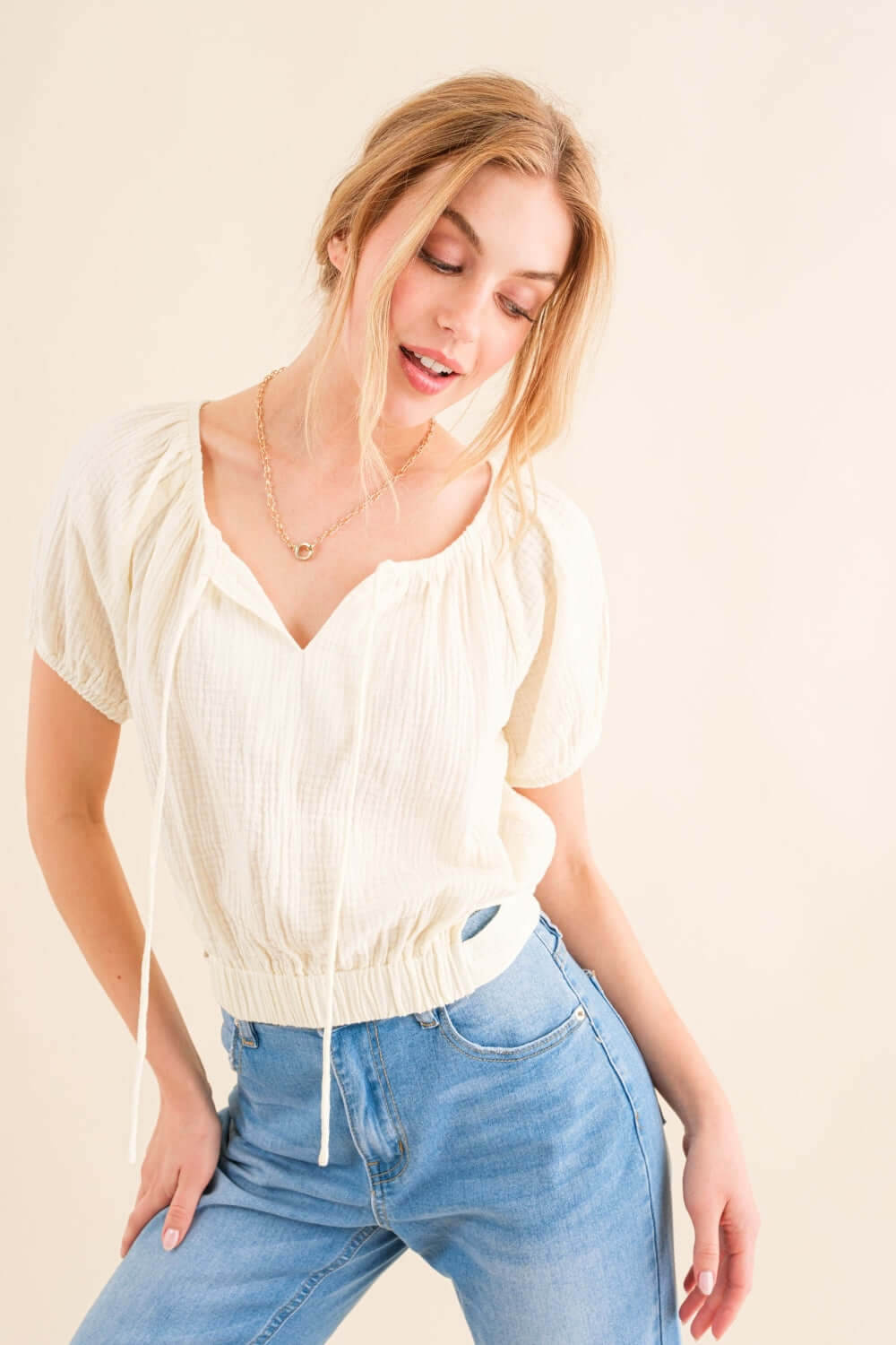 Woman wearing Back Waist Tie Cropped Blouse with high-waisted jeans, showcasing the stylish and versatile blouse with a flattering silhouette.