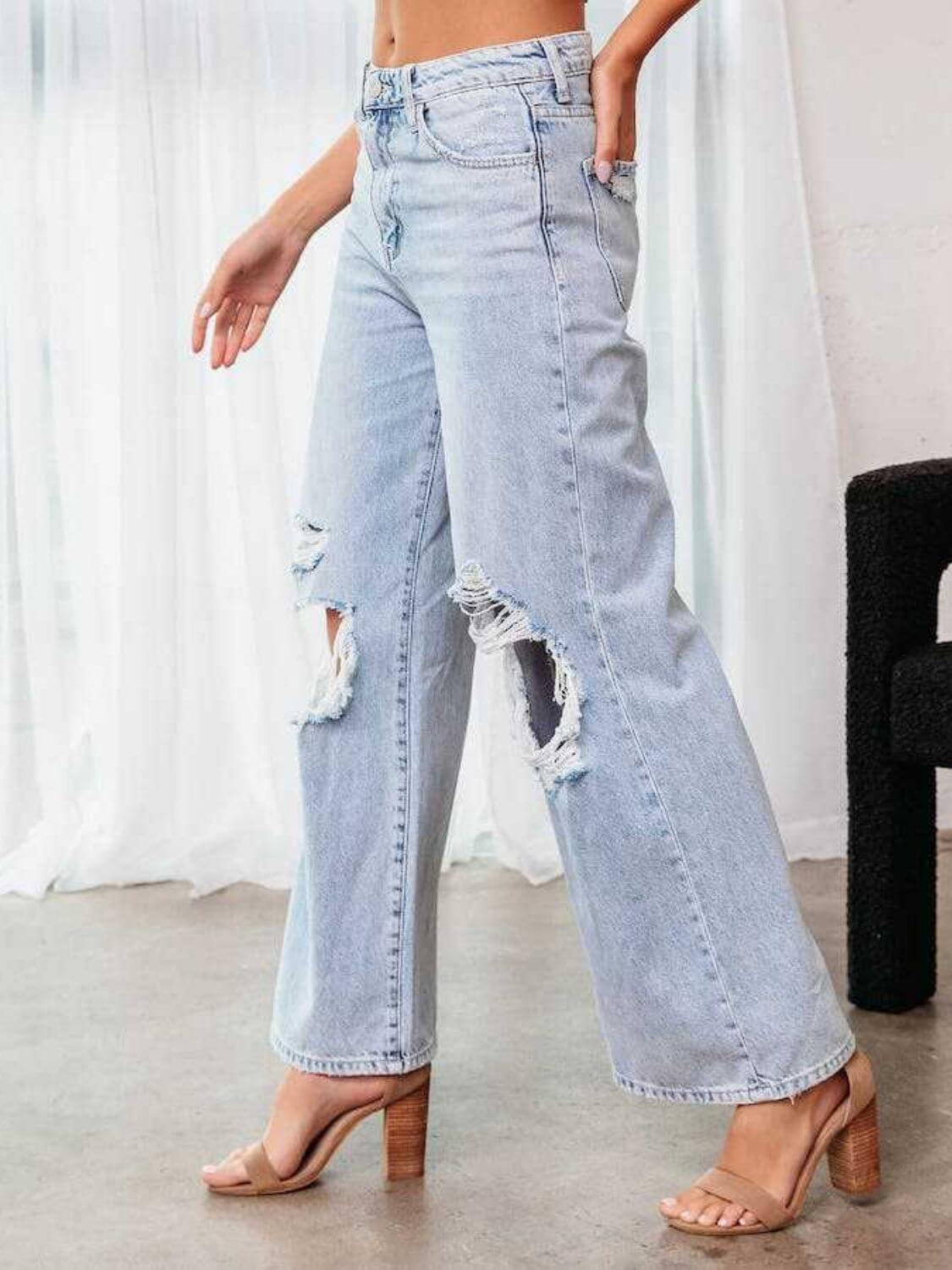 Woman wearing Bella Road Distressed Wide Leg Jeans with Pockets, shown with a side view highlighting the ripped details and loose fit.