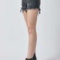 Woman wearing black raw hem denim shorts with pockets by Risen Jeans, styled with black ankle boots, perfect for casual summer looks