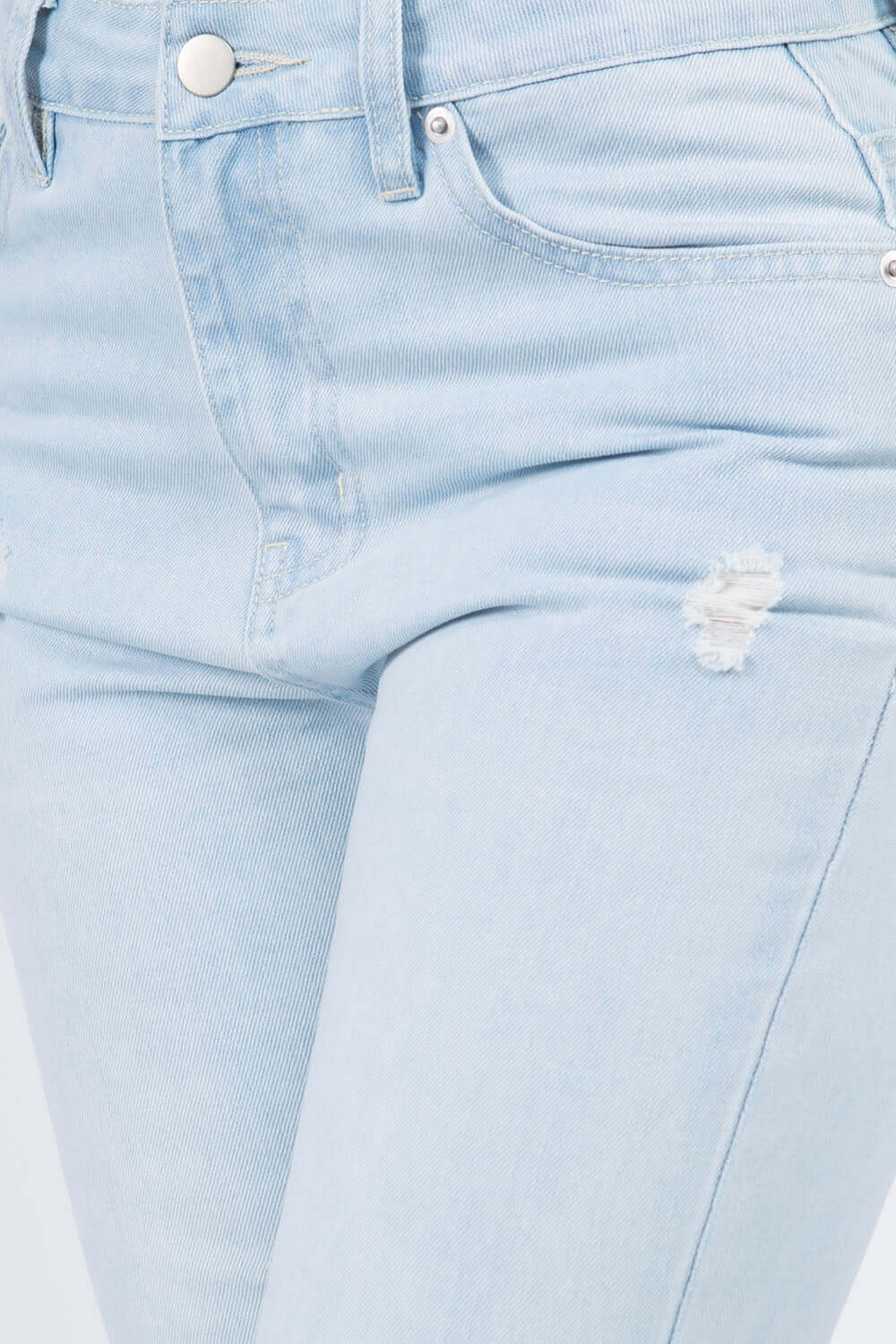 Close-up of high waist distressed raw hem jeans with trendy distressed detailing and modern raw hem finish.