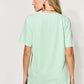 Woman wearing a MAMA round neck short sleeve t-shirt in green, back view.