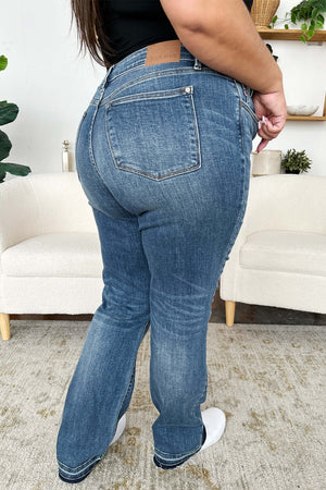 Woman wearing Judy Blue mid rise release hem jeans from the back view