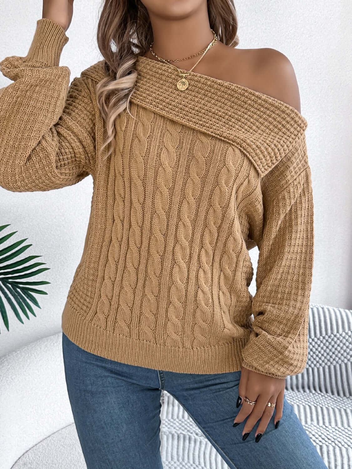 Woman wearing Bella Road Cable-Knit One Shoulder Long Sleeve Sweater in beige, paired with jeans, showcasing cozy and stylish design.