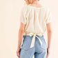 Back view of a stylish Back Waist Tie Cropped Blouse in light fabric, perfect for high-waisted pants or skirts.