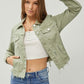 Model showcasing the RISEN cropped denim jacket with raw hem, styled with a casual top and jeans.