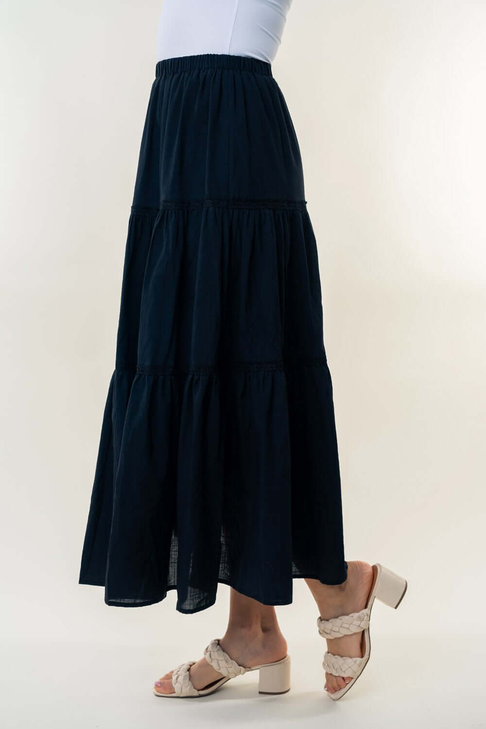 High Waisted Tiered Maxi Skirt in black, featuring a high-rise waist and flowy silhouette, paired with white top and braided sandals